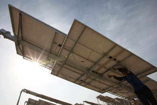 工人在新疆哈密光伏發電站安裝太陽能電池板組件